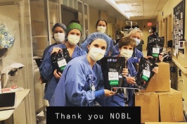 Emergency room workers at Tufts Medical Center holding bags of iced NOBL coffee