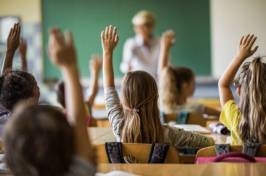 Students sat in a classroom raising their hands