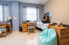 Student plays ukulele in UNH Downtown Commons dorm room