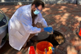 KELLEN SAWYER, A RESEARCH TECHNICIAN LEADING THE UNH SEWAGE MONITORING, RETRIEVES A SAMPLE FROM ONE OF THE MANHOLES 