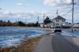 Car drives on flooded road near beach