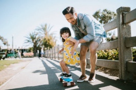 Image of girl learning to skateboard with dad