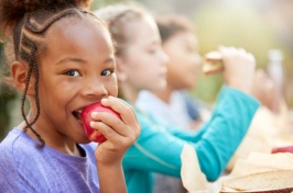 Image of girl eating apple accompanied by other kids