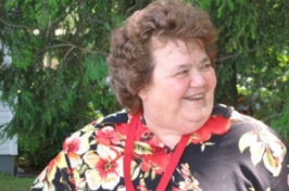 Marian West wearing a red and black floral shirt while standing outside in front of a tree.