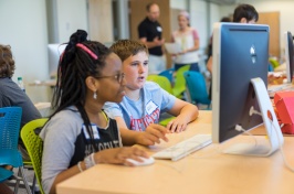 Two middle school students, a boy and a girl, work together on a computer.