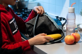 child taking healthy food out of backpack