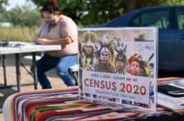 A photo of a Native American woman sitting at a 2020 Census table.