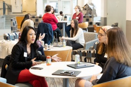 alumnae and students at round tables, talking, in Ham Smith Great Hall