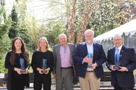 Five people stand side by side, some are holding glass plaques.