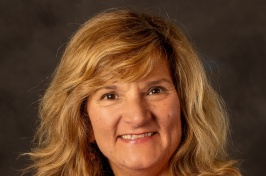 Headshot of Patricia Halpin, who has shoulder-length blonde hair and is wearing a bright pink jacket and necklace