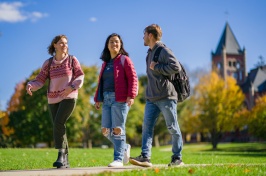 Three students walking on campus with Thompson Hall visible in the background