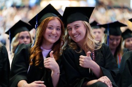 Two female students give the thumbs up at commencement