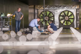 Three men work inside a large wind tunnel