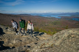 Three young people on rocky mountaintop with lake in background