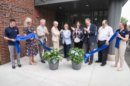 A crowd gathers around a ribbon for the official ribbon cutting ceremony at Spaulding Hall