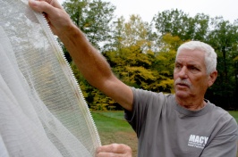 A man in a gray t-shirt holds up a net
