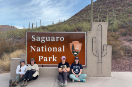 UNH graduate student Anna Frisbie (far right) and fellow researchers pose in front of entrance sign at Saguaro National Park in Arizona, 