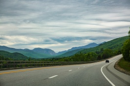 car driving on empty highway with mountains in backgroun
