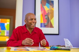 Man in a red shirt smiles while sitting at a table
