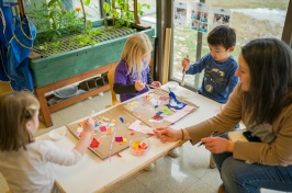 Three preschoolers play at a table with a female caregiver