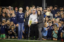UNH President Elizabeth Chilton, Greg and Corinna Tucker and UNH Director of Athletics Allison Rich surrounded by local youth athletic association members on Tucker Field