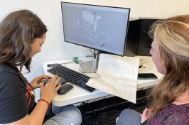 Two female students working at a desk with a computer on it