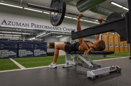 A woman lifts a bar with plates on it while bench pressing