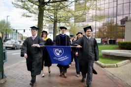 UNH Manchester Commencement participants walking with banner