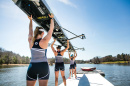 the UNH women’s crew team holding up their boat