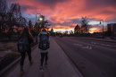 UNH students walking on Garrison Avenue against a colorful sunset over Thompson Hall