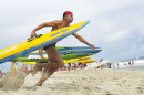 UNH alumnus Greg Johnson ’83 running with a surfboard at the beach (photo: Cape Cod Times)