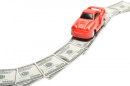 car driving along a road made of money