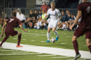 A member of the men's soccer team moves the ball downfield. 