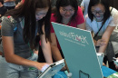 Three female college students gather around a video game