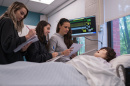 Students standing at the side of the "patient's" bed.