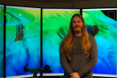 Drew Stevens stands in front of large computer screens.