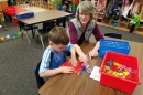 Photo of a teacher working with a student at a table in a classroom
