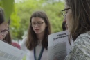 Three young women outside carrying research clipboards