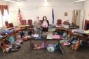 Two lawmakers hold up backpacks that were donated during an annual backpack drive.