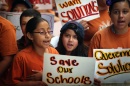 Grade school students wear orange shirts and hold protest signs.