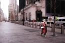 A single woman walks down an empty New York City street in a mask