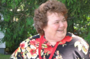 Marian West wearing a red and black floral shirt while standing outside in front of a tree.