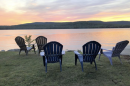 Adirondack chairs sit in front of a lake in Maine