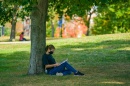 student sitting under tree reading 