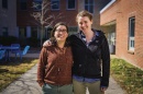 Two female graduate students stand outdoors with their arms around each other