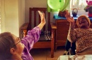 Two elderly women, one white and one Black, toss a green balloon