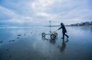 Female student pushes a GPS cart across a beach in winter