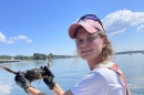 Female graduate student on a boat holding a male blue crab