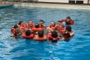 Group of people wearing lifejackets huddle in a circle in a pool