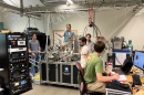 Five people work in a lab full of computers and other equipment
